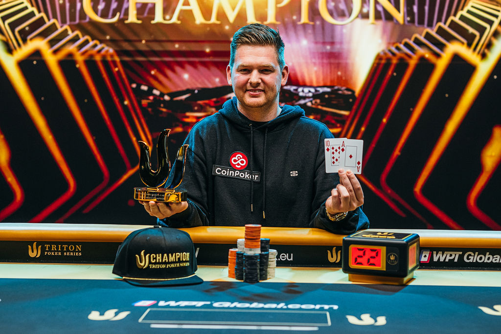 Poker champion at a high-stakes table holding a gold trident trophy