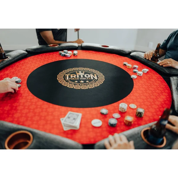 Overhead view of a poker table with red felt, chips, cards and a dealer button